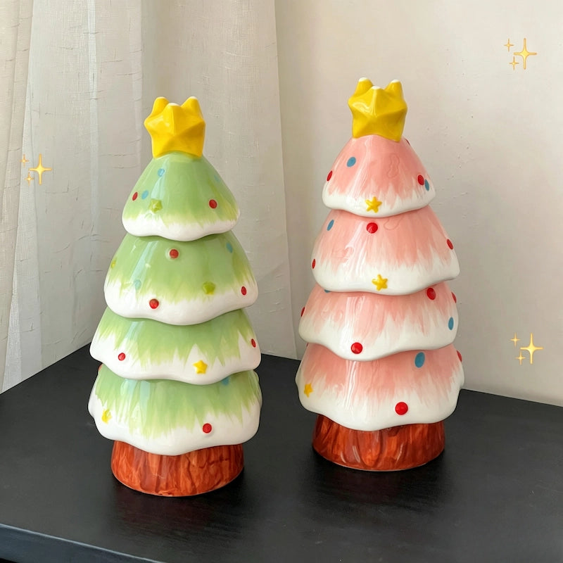 Green and pink ceramic Christmas tree figurines with yellow star tops on a dark surface